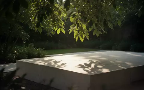 Sonnenlicht fällt durch grüne Blätter auf eine minimalistische Steinfläche in einem ruhigen Garten. - Foto: über boerse-global.de