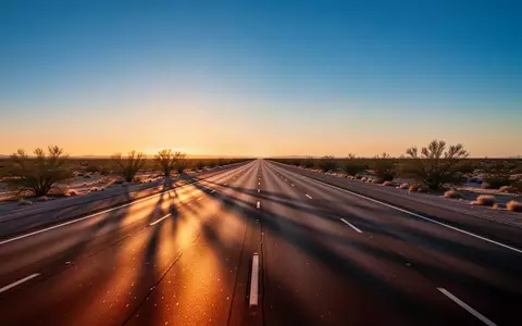 Eine leere, mehrspurige Autobahn in einer Wüstenlandschaft bei Sonnenuntergang mit klaren Fahrbahnmarkierungen. - Foto: über boerse-global.de