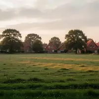 Eine weitläufige, unbebaute Grünfläche am Rande einer Ortschaft mit Blick auf entfernte Dächer bei natürlichem Tageslicht. - Foto: über boerse-global.de