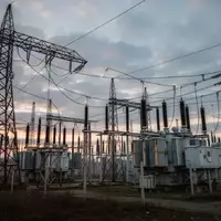 Hochspannungsmasten einer Stromtrasse in einer industriellen Landschaft bei Dämmerung. - Foto: über boerse-global.de