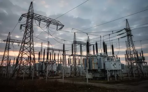 Hochspannungsmasten einer Stromtrasse in einer industriellen Landschaft bei Dämmerung. - Foto: über boerse-global.de