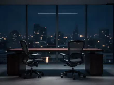 Ein unbesetzter, modern eingerichteter Büroraum bei Nacht mit Blick auf ein dunkles Stadtpanorama. - Foto: über boerse-global.de