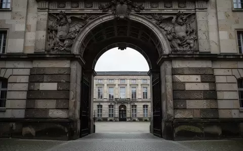 Ein schwerer, steinerner Torbogen führt in einen ruhigen, schattigen Innenhof eines Berliner Regierungsgebäudes. - Foto: über boerse-global.de