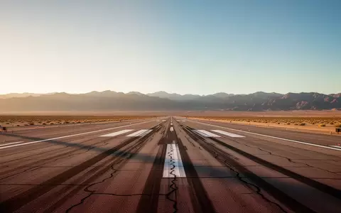 Eine leere, weitläufige Landebahn in einer Wüstenlandschaft bei Sonnenuntergang. - Foto: über boerse-global.de
