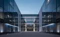 Modernes Verwaltungsgebäude bei Dämmerung mit geometrischer Glasfassade. - Foto: über boerse-global.de