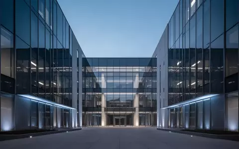 Modernes Verwaltungsgebäude bei Dämmerung mit geometrischer Glasfassade. - Foto: über boerse-global.de