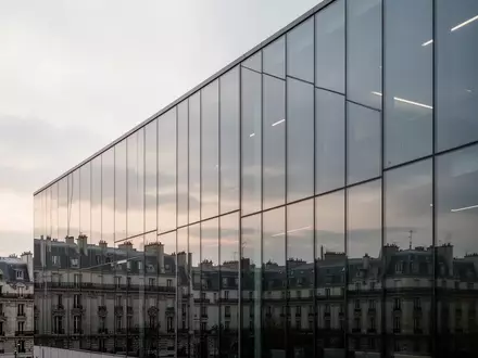 Eine moderne Glasfassade eines Bürogebäudes spiegelt das Licht am frühen Morgen wider. - Foto: über boerse-global.de