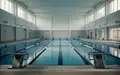 Ein leeres Hallenbad mit blauen Kacheln und Startblöcken in einer minimalistischen Architektur. - Foto: über boerse-global.de