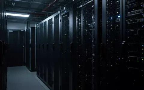 Dunkler, industrieller Serverraum mit metallischen Server-Racks in kühlem, blauem Licht. - Foto: über boerse-global.de