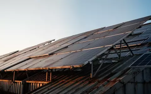 Eine weitläufige Photovoltaikanlage auf einem Industriedach unter einem klaren Morgenhimmel. - Foto: über boerse-global.de