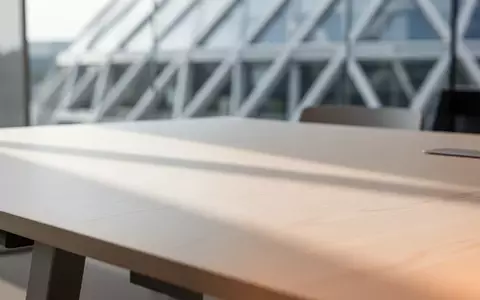 Ein minimalistischer Arbeitsplatz mit einer leeren Holzoberfläche und unscharfer, moderner Architektur im Hintergrund. - Foto: über boerse-global.de