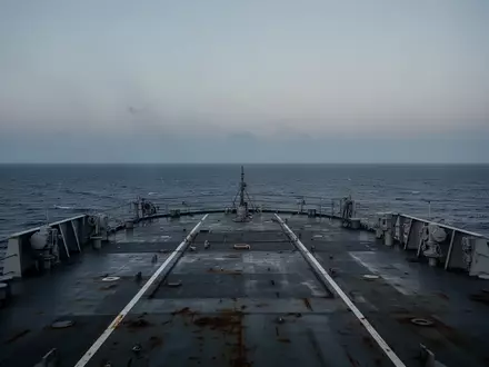 Blick über das leere, stählerne Deck eines großen Schiffes auf den weiten, ruhigen Ozean bei Dämmerung. - Foto: über boerse-global.de