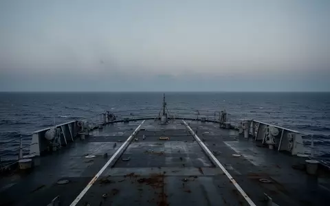 Blick über das leere, stählerne Deck eines großen Schiffes auf den weiten, ruhigen Ozean bei Dämmerung. - Foto: über boerse-global.de