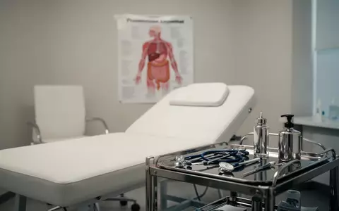 Ein minimalistisch eingerichtetes, helles Arztzimmer mit medizinischen Instrumenten und einem anatomischen Schaubild. - Foto: über boerse-global.de