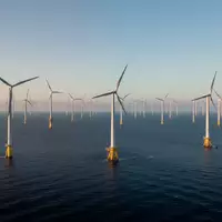 Ein moderner Offshore-Windpark vor einer ruhigen Meeresküste bei Sonnenaufgang. - Foto: über boerse-global.de