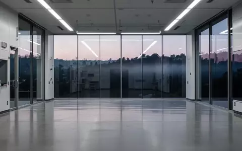 Ein minimalistisches, leeres High-Tech-Labor im Silicon Valley mit großen Glasfenstern und Blick auf eine dunkle Hügellandschaft. - Foto: über boerse-global.de