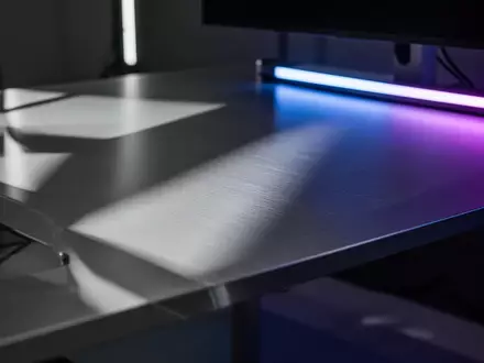 Ein minimalistischer, moderner Arbeitsplatz mit einer gebürsteten Aluminiumoberfläche und subtiler blauer Beleuchtung. - Foto: über boerse-global.de