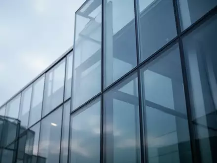 Abstrakte Architekturaufnahme eines modernen Glasgebäudes bei bewölktem Himmel zur Symbolisierung digitaler Sicherheitsrisiken. - Foto: über boerse-global.de