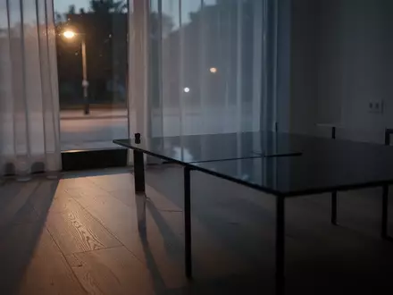 Ein minimalistisch eingerichteter Raum bei Dämmerung mit Fokus auf eine dunkle, spiegelnde Oberfläche und weichem Licht. - Foto: über boerse-global.de