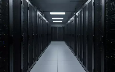 Dunkler Korridor in einem Rechenzentrum mit schlichten, unbeschrifteten Serverschränken in kühler, bläulicher Beleuchtung. - Foto: über boerse-global.de