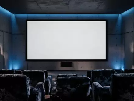 Ein minimalistisch gestaltetes, abgedunkeltes Heimkino mit einer großen, leeren Projektionsfläche an einer Betonwand. - Foto: über boerse-global.de