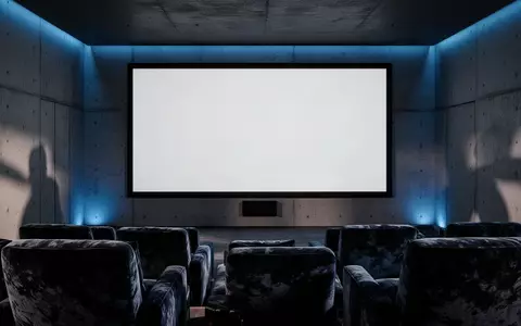 Ein minimalistisch gestaltetes, abgedunkeltes Heimkino mit einer großen, leeren Projektionsfläche an einer Betonwand. - Foto: über boerse-global.de