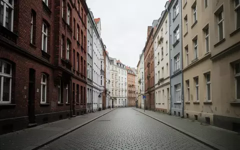 Eine menschenleere Straße in einem Berliner Wohnviertel mit historischer Architektur unter einem grauen Himmel. - Foto: über boerse-global.de