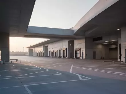 Ein minimalistisches, modernes Logistik-Terminal bei Tagesanbruch mit klaren architektonischen Linien und Betonflächen. - Foto: über boerse-global.de