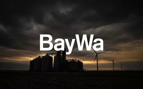 Düstere Industrielandschaft mit Silos und Windkraftanlagen bei Dämmerung als Symbol für wirtschaftliche Sanierung. - Foto: über boerse-global.de