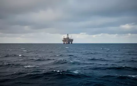 Eine weitläufige Aufnahme der Nordsee mit einer einsamen Offshore-Plattform am fernen Horizont unter einem bewölkten Himmel. - Foto: über boerse-global.de