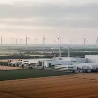 Weite Industrielandschaft mit Windkraftanlagen und modernen Fabrikgebäuden in Ostdeutschland bei Sonnenaufgang. - Foto: über boerse-global.de