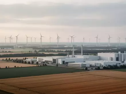 Weite Industrielandschaft mit Windkraftanlagen und modernen Fabrikgebäuden in Ostdeutschland bei Sonnenaufgang. - Foto: über boerse-global.de