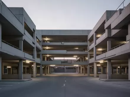 Ein modernes, minimalistisches Parkhaus in der Dämmerung mit architektonischen Linien aus Beton. - Foto: über boerse-global.de