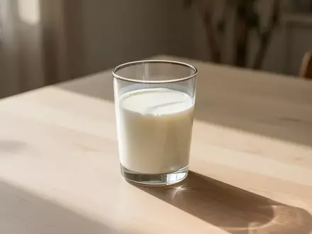 Ein Glas mit frischer Milch auf einem hellen Holztisch in hellem Morgenlicht. - Foto: über boerse-global.de