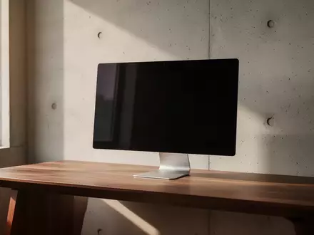Ein minimalistischer Arbeitsplatz mit einem ausgeschalteten Monitor und natürlichem Lichteinfall in einer modernen Büroumgebung. - Foto: über boerse-global.de