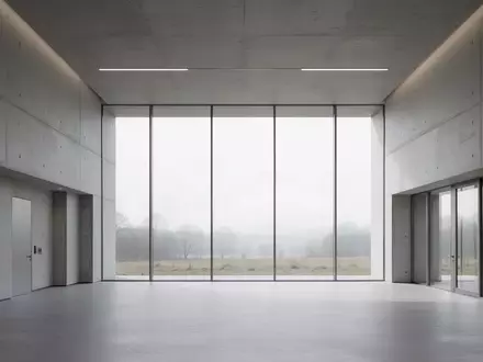 Ein minimalistischer, leerer Flur in einem modernen Verwaltungsgebäude mit großen Fenstern und Blick auf eine Landschaft. - Foto: über boerse-global.de