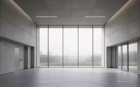 Ein minimalistischer, leerer Flur in einem modernen Verwaltungsgebäude mit großen Fenstern und Blick auf eine Landschaft. - Foto: über boerse-global.de