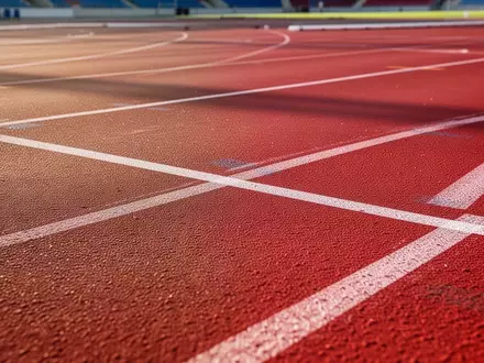 Rote Kunststoffbahn in einem Stadion mit weißen Markierungen bei Tageslicht. - Foto: über boerse-global.de