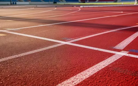 Rote Kunststoffbahn in einem Stadion mit weißen Markierungen bei Tageslicht. - Foto: über boerse-global.de