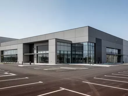 Ein modernes, großflächiges Einzelhandelsgebäude mit Parkplatz bei Tageslicht. - Foto: über boerse-global.de