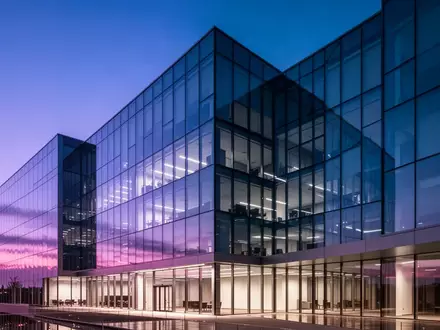 Ein modernes, minimalistisches Bürogebäude in der Abenddämmerung mit blau-violetten Reflexionen. - Foto: über boerse-global.de