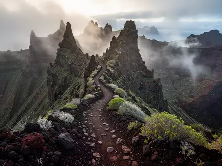 Ein steiler, zerklüfteter Pfad führt durch die neblige, vulkanische Berglandschaft von La Gomera. - Foto: über boerse-global.de