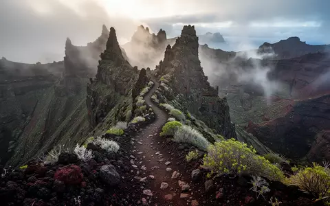 Ein steiler, zerklüfteter Pfad führt durch die neblige, vulkanische Berglandschaft von La Gomera. - Foto: über boerse-global.de