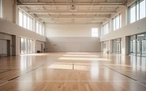 Helle, moderne Sporthalle mit hellem Holzboden und groĂen Fenstern ohne Personen. - Foto: ĂŒber boerse-global.de