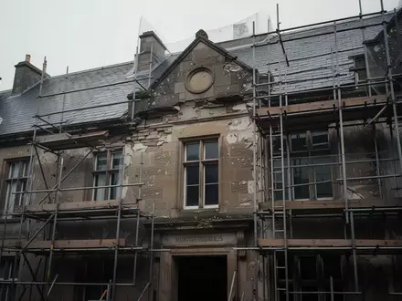 Fassade eines historischen, renovierungsbedürftigen öffentlichen Gebäudes mit Gerüst vor grauem Himmel - Foto: über boerse-global.de