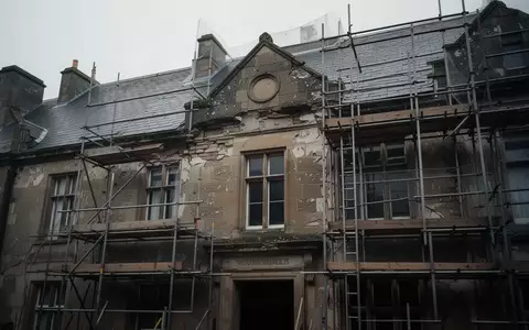 Fassade eines historischen, renovierungsbedürftigen öffentlichen Gebäudes mit Gerüst vor grauem Himmel - Foto: über boerse-global.de