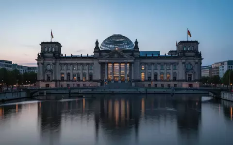 Das Berliner Reichstagsgebäude in der Abenddämmerung bei blauem Licht mit Spiegelung im Wasser der Spree. - Foto: über boerse-global.de
