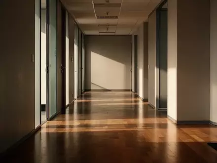 Ein leerer, sonnendurchfluteter Büroflur mit langen Schatten auf dem Boden, der eine Atmosphäre der Stille vermittelt. - Foto: über boerse-global.de