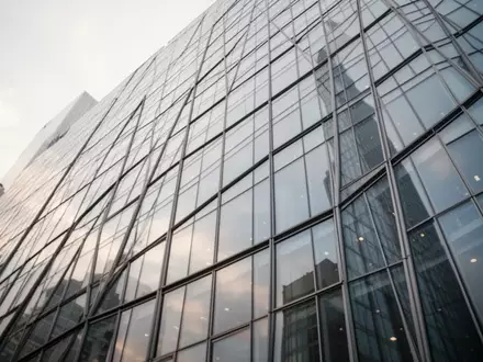 Großflächige Glasfassade eines modernen Bürogebäudes bei bewölktem Himmel - Foto: über boerse-global.de
