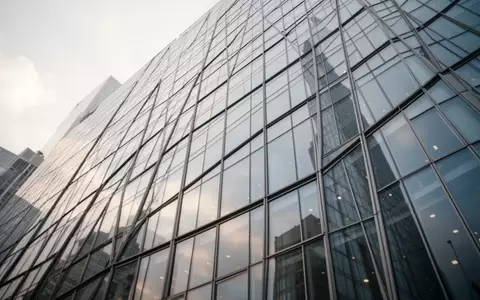 Großflächige Glasfassade eines modernen Bürogebäudes bei bewölktem Himmel - Foto: über boerse-global.de